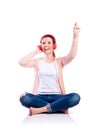 Woman with earphones sitting on the floor, studio shot, isolated Royalty Free Stock Photo