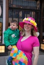 Woman in Easter egg hat holding her child at Easter Bonnet Parae