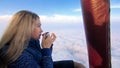 Woman eat sandwich and drinks tea and coffee in flight. Adventure on hot air balloon. Fly in morning blue sky above