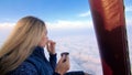 Woman eat sandwich and drinks tea and coffee in flight. Adventure on hot air balloon. Fly in morning blue sky above