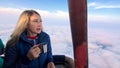 Woman eat sandwich and drinks tea and coffee in flight. Adventure on hot air balloon. Fly in morning blue sky above