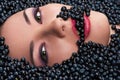 Woman is eating blueberries lying in blueberries
