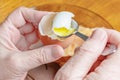 Woman eating boiled chicken egg with teaspoon against plate of dark glass with bread on the wooden table Royalty Free Stock Photo