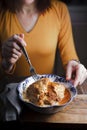 Woman eating from a bowl of chicken Butter partial blur