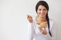 Woman Eating Bowl Of Fresh Fruit Against White Background