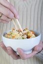 Woman eating three delights rice witn chopsticks