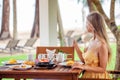 Woman eating breakfast, drinking coffee in cafe in tropical resort