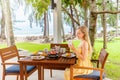 Woman eating breakfast, drinking coffee in cafe in tropical resort