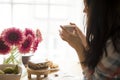 A woman is eating breakfast at the window, on the table a bouquet of flowers and fragrant coffee. Good morning at home. Free space