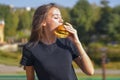 Woman eating burger and fries smiling. Beautiful caucasian female model eating a hamburger with hands Royalty Free Stock Photo