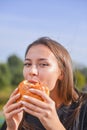 Woman eating burger and fries smiling. Beautiful caucasian female model eating a hamburger with hands Royalty Free Stock Photo