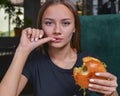 Woman eating burger and fries smiling. Beautiful caucasian female model eating a hamburger with hands Royalty Free Stock Photo