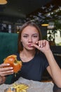 Woman eating burger and fries smiling. Beautiful caucasian female model eating a hamburger with hands Royalty Free Stock Photo