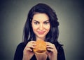 Woman eating burger smiling. Beautiful female model Royalty Free Stock Photo