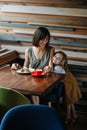 Happy woman eating cake in a cafe, while her daughter showing her affection Royalty Free Stock Photo