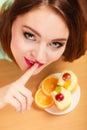 Woman eating cake showing quiet sign. Gluttony.