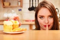 Woman eating cake showing quiet sign. Gluttony.