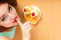 Woman eating cake showing quiet sign. Gluttony.