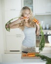 Woman eating carrot at kitchen counter Royalty Free Stock Photo