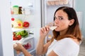 Woman Eating Cheese In Front Of Refrigerator Royalty Free Stock Photo