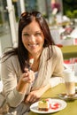 Woman eating cheesecake at cafe bar happy