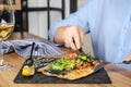 Woman eating delicious grilled fish at wooden table indoors Royalty Free Stock Photo