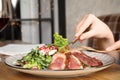 Woman eating delicious salad with roasted duck breast at wooden table, closeup Royalty Free Stock Photo