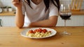 Woman eating dish from white plate in kitchen. Close up of women's hands pricking macaroni on fork. Royalty Free Stock Photo