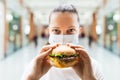 Woman Eating Fastfood Burger In Face Mask