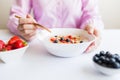 Woman eating fresh muesli with milk and fruits at the table Royalty Free Stock Photo