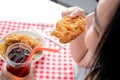Woman eating fried chicken with a glass of soft drink