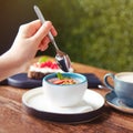 Woman eating fruit pudding and drinking cappuccino coffee on a table in a summer restaurant, close up Royalty Free Stock Photo