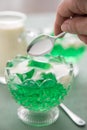 Woman eating green woodruff jelly and vanilla custard with spoon