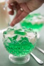 Woman eating green woodruff jelly and vanilla custard with spoon