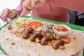 Woman eating grilled kebab with pita bread and vegetables on tray in summer fast food street cafe