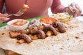 Woman eating grilled kebab with pita bread and vegetables on tray in summer fast food street cafe