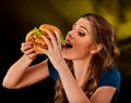 Woman eating hamburger. Student consume fast food on table.