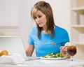 Woman eating healthy lunch while typing on laptop Royalty Free Stock Photo