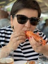 Woman Eating Huge Langoustine In Food Court Of A Seafood Market In Trouville, France