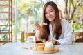 A woman eating ice cream with a mixed berries pancakes and whipped cream by wooden spoon Royalty Free Stock Photo