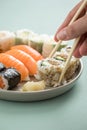 Woman eating Japanese tuna avocado inside out California with salmon Nigiri and Maki from sushi mix plate with wooden chopsticks Royalty Free Stock Photo