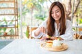 A woman eating a mixed berries pancakes with ice cream and whipped cream by wooden spoon Royalty Free Stock Photo