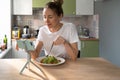 Woman eating pasta with vegetarian pesto sauce, addicted to social networks, watching movie on phone Royalty Free Stock Photo