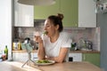 Woman eating pasta with vegetarian pesto sauce, watching movie on smart phone on tripod at home. Royalty Free Stock Photo