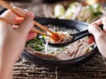 Woman eating pho with sriracha using chopsticks and spoon together Royalty Free Stock Photo