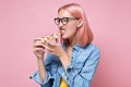 Woman eating a piece of pizza against a pink background Royalty Free Stock Photo