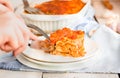 Woman eating piece of tasty hot lasagna served on a white plate. Italian cuisine, menu, recipe. Homemade meat lasagna. Close up, Royalty Free Stock Photo