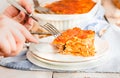 Woman eating piece of tasty hot lasagna served on a white plate. Italian cuisine, menu, recipe. Homemade meat lasagna. Close up, Royalty Free Stock Photo
