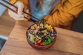 Woman eating Raw Organic Poke Bowl with Rice and Veggies close-up on the table. Top view from above horizontal Royalty Free Stock Photo