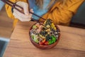 Woman eating Raw Organic Poke Bowl with Rice and Veggies close-up on the table. Top view from above horizontal Royalty Free Stock Photo